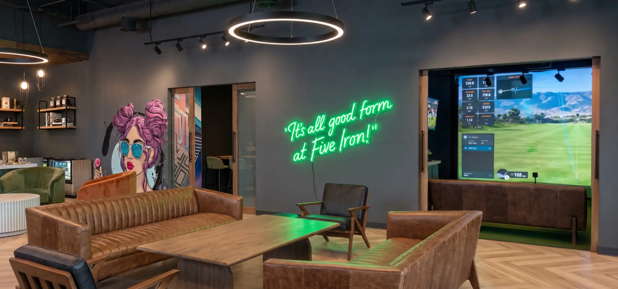 Five Iron Studio lounge with café counter, seating, art, and green neon sign